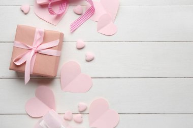 Beyaz ahşap arka planda pembe kalpleri olan hediye kutuları. Sevgililer Günü kutlaması