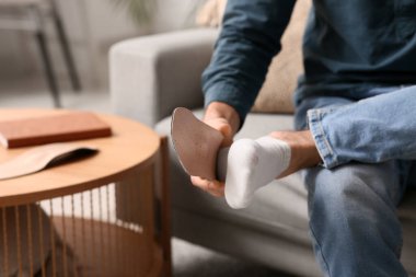 Genç adam evdeki kanepeye ortopedik taban uyguluyor, yakın plan.