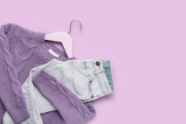 Süslü çocuk süveteri ve leylak arka planda kot pantolon askısı.