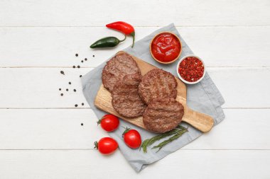 Lezzetli et pirzolaları, biberler, domatesler ve baharatlar beyaz ahşap arka planda.