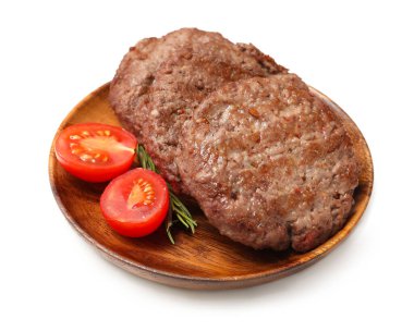 Beyaz arka planda lezzetli et pirzolaları, domatesler ve biberiyeli ahşap tabak.