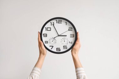 Odadaki beyaz duvara kadın eli saati asıyor. Yakın çekim.