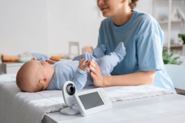 Anneye karşı bebek monitörü, çocuğu yatak odasında masasını değiştirirken, yakın çekim.