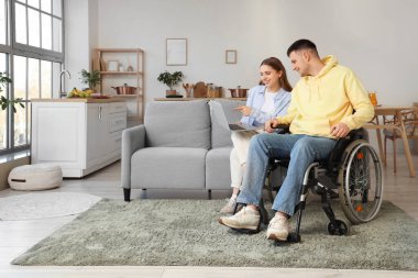 Tekerlekli sandalyedeki genç adam ve evinde dizüstü bilgisayarı olan kız arkadaşı.