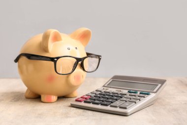 Gri arkaplanda hesap makinesi olan kumbara.