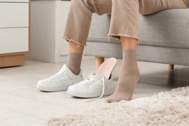 Genç bir kadın spor ayakkabılarına ortopedik taban takıyor.