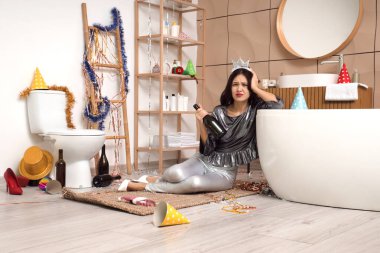 Genç Asyalı kadın banyodaki partiden sonra küvetin yanında kendini kötü hissediyor.