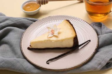 Bir parça vanilyalı cheesecake ve sarı arka planda bir bardak çay.