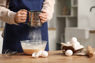 Baker mutfakta bisküvi hamuruna elek ile un ekliyor. Yakın çekim.