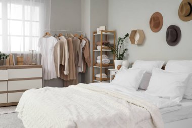Konforlu yatak, raf ünitesi ve yatak odasının iç tarafında giysi rafı.