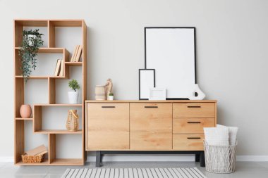 Raflama ünitesi, çekmece sandığı ve odadaki bej duvarın yanındaki boş fotoğraf çerçeveleri.