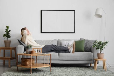 Oturma odasındaki kanepede yatan genç kadın.