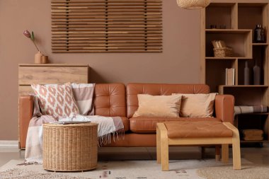 Oturma odasının iç tarafında rahat bir kanepe, ayaklık ve hasır sepet.