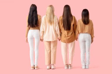 Pembe arka planda el ele tutuşan bir grup genç kadın. Kadın Tarihi Ayı