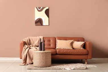 Sıcak kanepe ve kahve masası. Odada kahverengi duvarın yanında şişeler var.