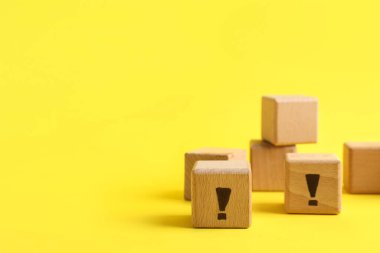 Sarı zemin üzerinde ünlem işaretleri olan tahta küpler.