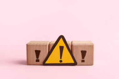 Tahta küpler ve pembe arka planda ünlem işaretleri olan kağıt üçgen.