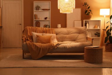 Oturma odasının iç tarafında dizüstü bilgisayarı olan rahat bir kanepe ve hasır sepet.