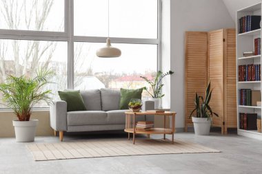 Raflar, kitaplar, kanepe ve sehpa şık bir oturma odasının içinde.