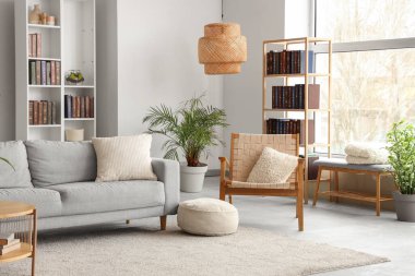 Kitaplıklar, rahat bir kanepe ve modern oturma odasının içindeki hasır koltuk.