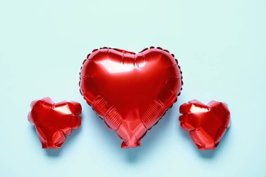 Kırmızı kalp şekilli hava balonları mavi arka planda