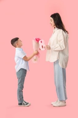 Sevimli küçük çocuk pembe arka planda Uluslararası Kadınlar Günü 'yle annesini selamlıyor.