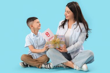 Sevimli küçük çocuk mavi arka planda Uluslararası Kadınlar Günü 'yle annesini selamlıyor.