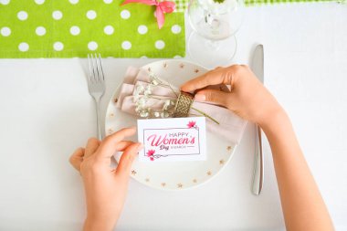 Uluslararası Kadınlar Günü kutlamaları için tebrik kartı ve basit masa düzeniyle kadın elleri, yakın plan.