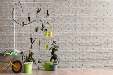 Bahçe aletleri ve atölyedeki gri tuğla duvarın yanındaki bitkilerle dolu bir tahta.