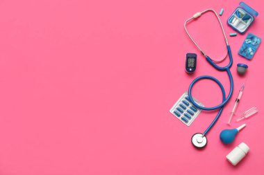 Nabız oksimetresi, şırınga, steteskop ve pembe arka plandaki ilaçlarla bileşim
