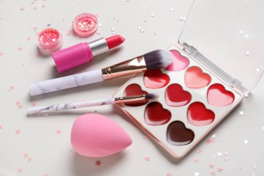 Parıltı kavanozu, konfeti, makyaj ürünleri ve beyaz arkaplanda fırçalar içeren kompozisyon, yakın plan