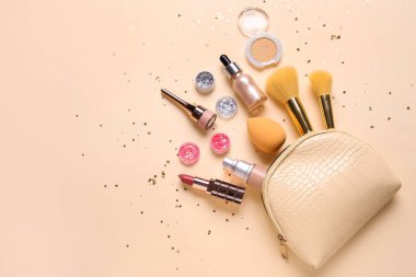 Kozmetik çantalı kompozisyon, parlak kavanozlar, pullar, makyaj ürünleri ve bej arka planda aksesuarlar.