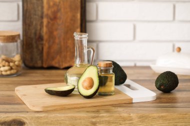 Beyaz tuğla duvarın yanındaki ahşap masada bir şişe taze avokado yağı.