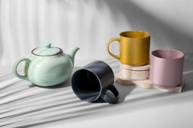 Beyaz arka planda farklı seramik bardaklar, çaydanlık ve alçı tezgahları.