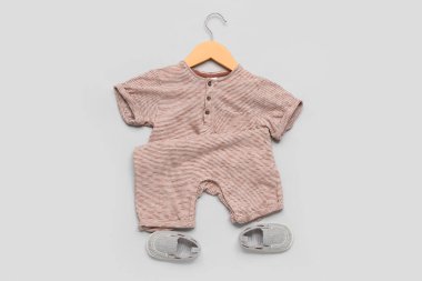 Süslü bebek kıyafetleri ve gri arka planda kalçaları olan bir askı.