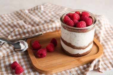 Bej arka planda lezzetli ahududulu cheesecake bardağı