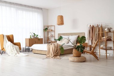 Giysileri ve aksesuarları olan modern konforlu bir yatak odası.