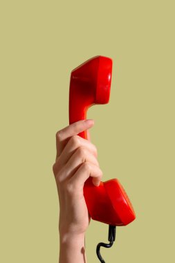 Yeşil arka planda retro telefonu olan bir kadın el.