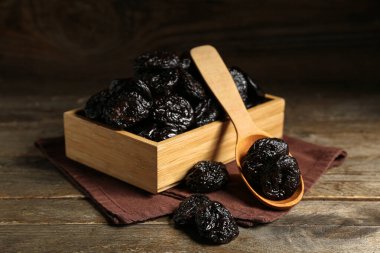 Tahta arka planda kurutulmuş kuru erikli kutu ve kaşık.