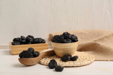 Beyaz ahşap arka planda kuru erikli kase ve kaşık.