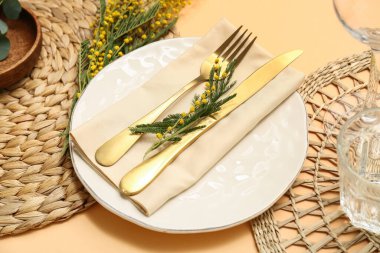 Turuncu arka planda mimoza çiçekleri olan güzel bir masa, yakın plan.