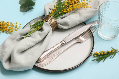 Mimoza çiçekleri ve mavi arka planda okaliptüs olan güzel masa ayarı, yakın plan.