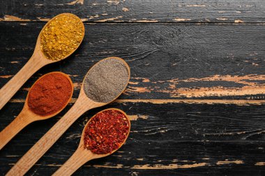 Koyu ahşap arka planda taze aromalı kaşıklar.