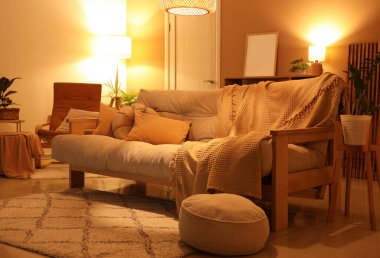 Oturma odasının içinde rahat bir kanepe ve parlayan lambalar.