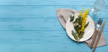 Mimoza çiçekleri ve okaliptüs ile güzel masa ayarları mavi ahşap zemin üzerinde metin için alan ile