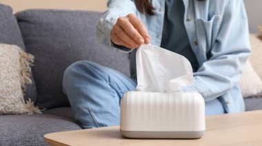 Kadın masadaki seramik tutucudan doku alıyor.