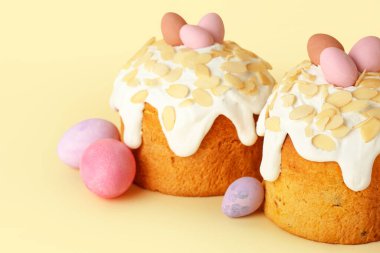 Paskalya pastaları ve sarı arka planda boyanmış yumurtalar.