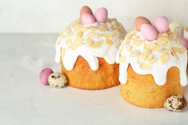 Easter cakes and painted eggs on table near white wall