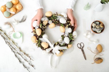 Beyaz masasında Paskalya çelengi olan bir kadın.