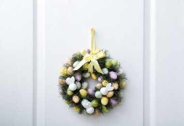 Beyaz ahşap kapıya asılı Paskalya çelengi